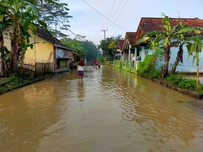 Warga melintas di jalan yang digenangi air akibat meluapnya Sungai Citanduy dan Cikidang di Kecamatan Sukaresik, Kabupaten Tasikmalaya. (Foto: MI/Kristiadi)