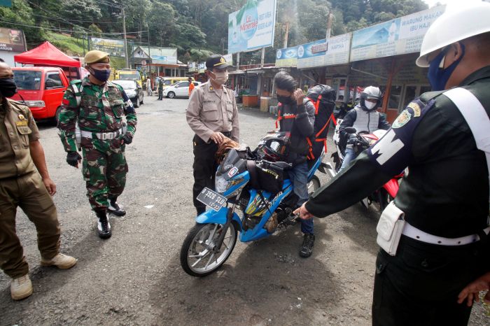 Polisi menghentikan pengendara sepeda motor diduga mudik di perbatasan Cianjur-Bogor. Antara/Yulius Satria Wijaya