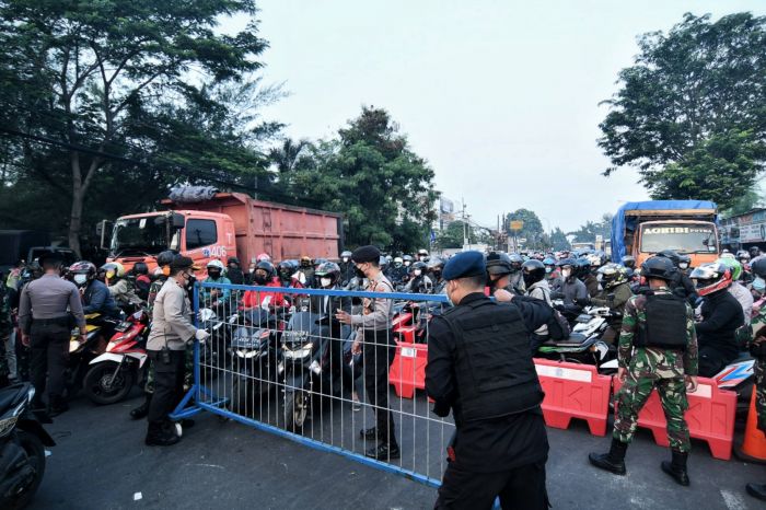 Petugas memasang barrier untuk menutup jalan di pos penyekatan jalan Raya Bogor, Jakarta. Foto: MI/Andri Widiyanto