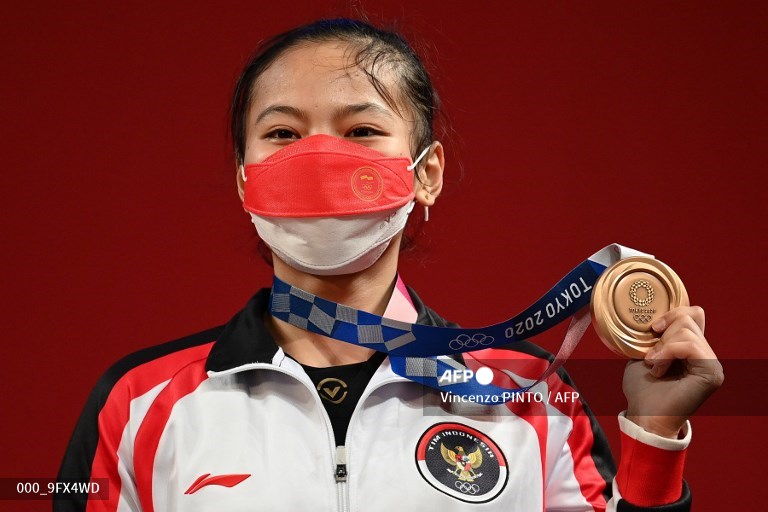 Atlet angkat besi Indonesia, Windy Cantika Aisah, memamerkan medali perunggu yang ia raih di Olimpiade Tokyo (AFP/Vincenzo Pinto)