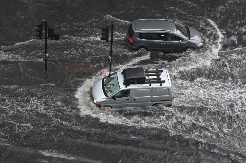 Warga Inggris mengemudikan kendaraan mereka di tengah banjir di kota London, 25 Juli 2021. (JUSTIN TALLIS / AFP)