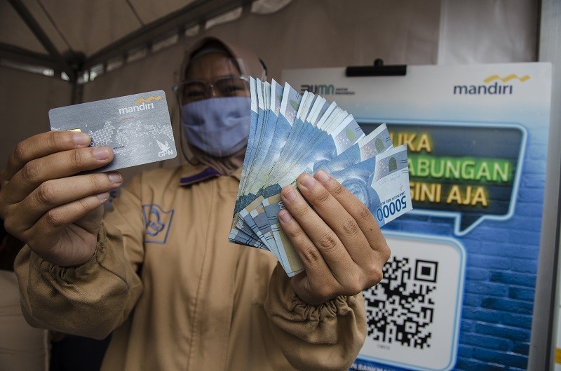  Ilustrasi--Seorang pekerja menunjukkan kartu ATM dan uang saat menerima Bantuan Subsidi Upah (BSU) di halaman PT Perusahaan Industri Ceres, Kabupaten Bandung, Jawa Barat. (ANTARA/Novrian Arbi)