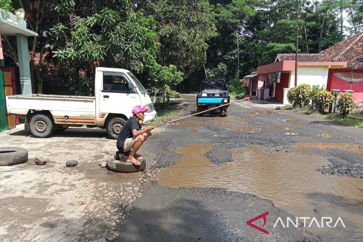 Warga di Kecamatan Sindangbarang, Cianjur, Jawa Barat, melakukan aksi protes rusaknya jalan provinsi dengan cara memancing ikan di jalan yang berlubang, agar segera mendapat pembangunan. Foto: Antara/Ahmad Fikri
