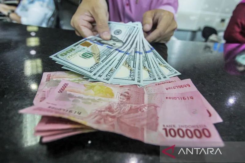 Ilustrasi - Petugas menunjukan uang pecahan rupiah dan dolar Amerika Serikat (AS) di tempat penukaran mata uang asing di Jakarta. ANTARA FOTO/Muhammad Adimaja/hp/aa. ANTARA FOTO/MUHAMMAD ADIMAJA.