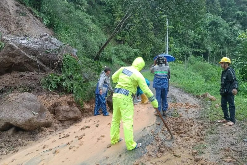 Polisi dan masyarakat berupaya menyingkirkan material longsoran tanah dan bebatuan yang menutupi badan jalan di Pamulihan, Kabupaten Garut, Jawa Barat. (ANTARA/HO-Polsek Pamulihan)