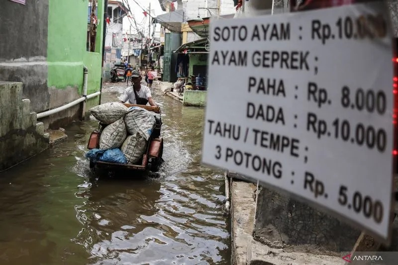 Arsip Foto. Pengendara becak motor melintasi jalanan yang terendam banjir rob di daerah Muara Angke, Jakarta, Rabu (7/12/2022). (ANTARA FOTO/DARRYL RAMADHAN)