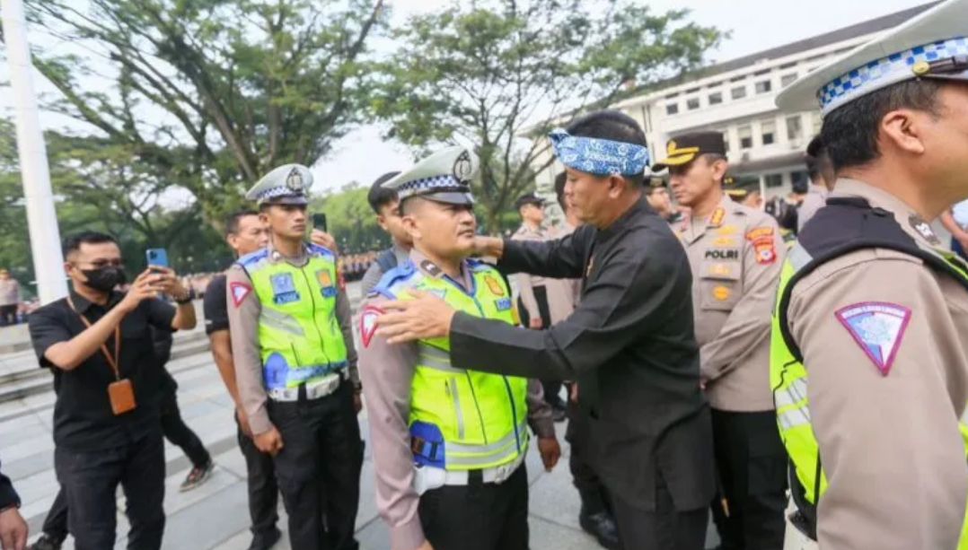 Pelaksana Harian (Plh) Wali Kota Bandung Ema Sumarna didampingi Kapolrestabes Bandung Kombes Pol Budi Sartono menyematkan bange pada perwakilan petugas Polisi RW dalam peluncuran program Polisi RW Kota Bandung di Balai Kota Bandung, Kamis (11/5/2023). (AN