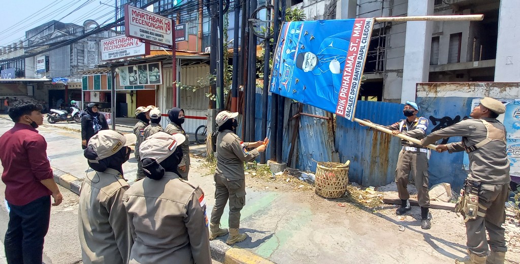 Petugas Satpol PP Cilegon menertibkan APK liar milik salah seorang bacaleg partai di jalan protokol. (Gilang)